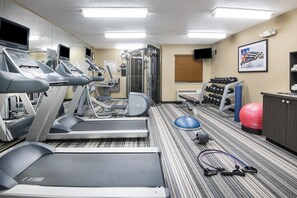 Un gimnasio con cintas de correr, máquinas de pesas y pelotas de ejercicio.