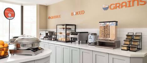 A breakfast bar with a griddle, a coffee machine, and various food containers.