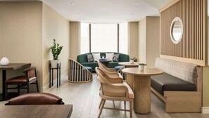 A modern interior with a green sofa, wooden chairs, a round table, and a wooden partition with a mirror.