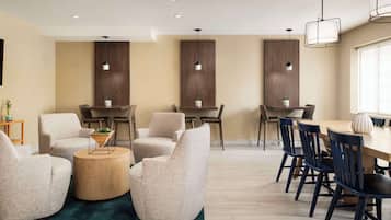 A modern dining area with round tables and chairs, a wooden accent wall, and pendant lighting.