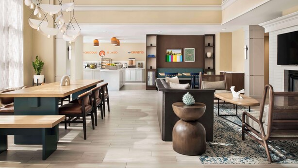 A spacious living area with a dining table, seating, a fireplace, and a kitchen in the background.