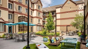 A courtyard with outdoor seating, a dartboard, and potted plants.