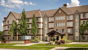 A multi-story hotel with a central entrance, surrounded by well-maintained lawns and trees.