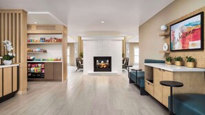 A modern living area with a fireplace, seating, and a reception desk with snacks.