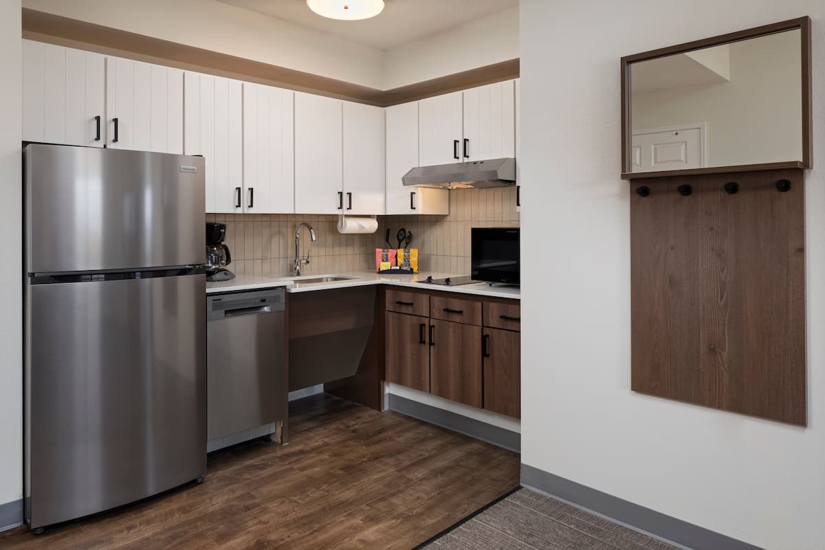 A modern kitchen with stainless steel appliances, wooden cabinets, and a built-in microwave.