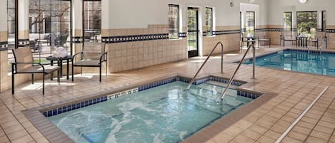A swimming pool with a tiled deck, chairs, and a view of the outdoors.