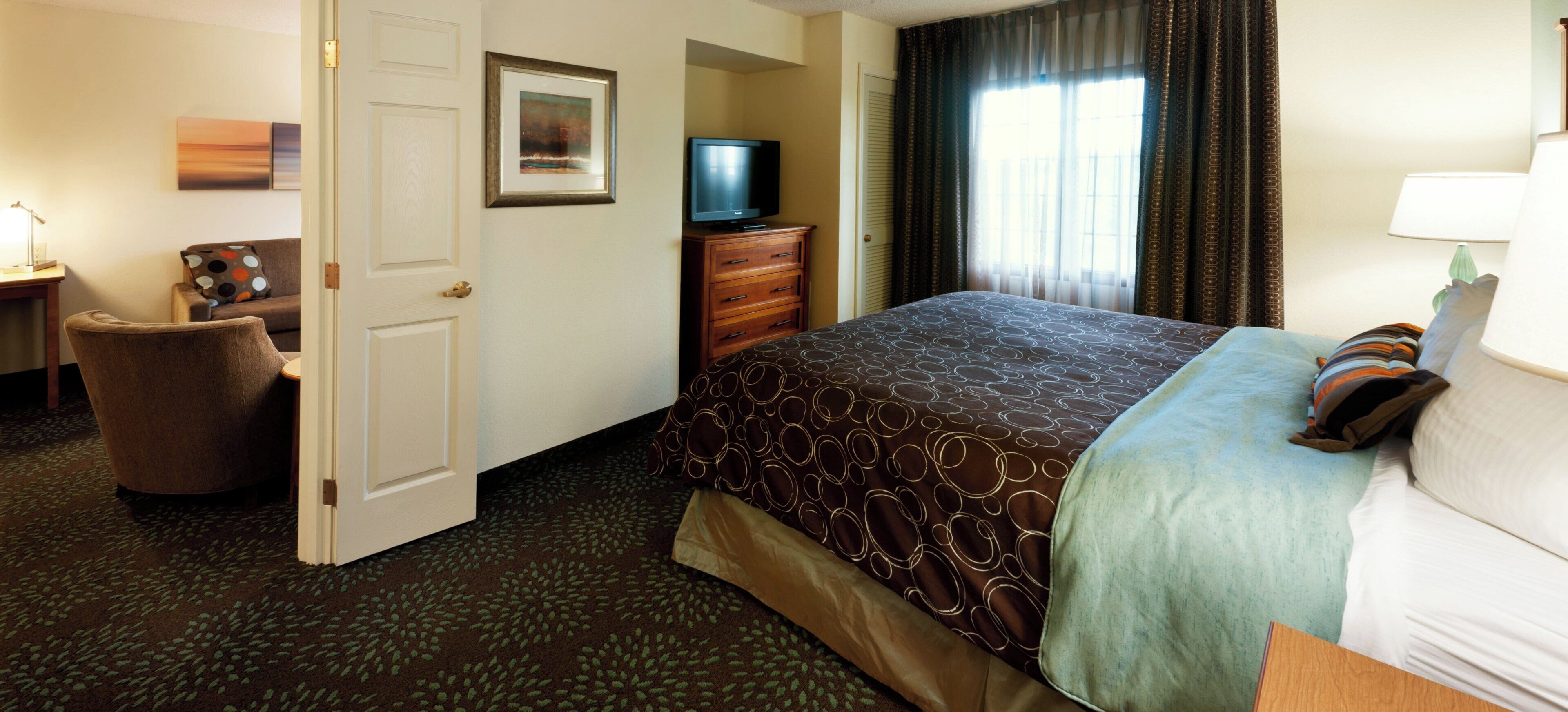 A hotel room with a bed, a television, a desk, and a chair.