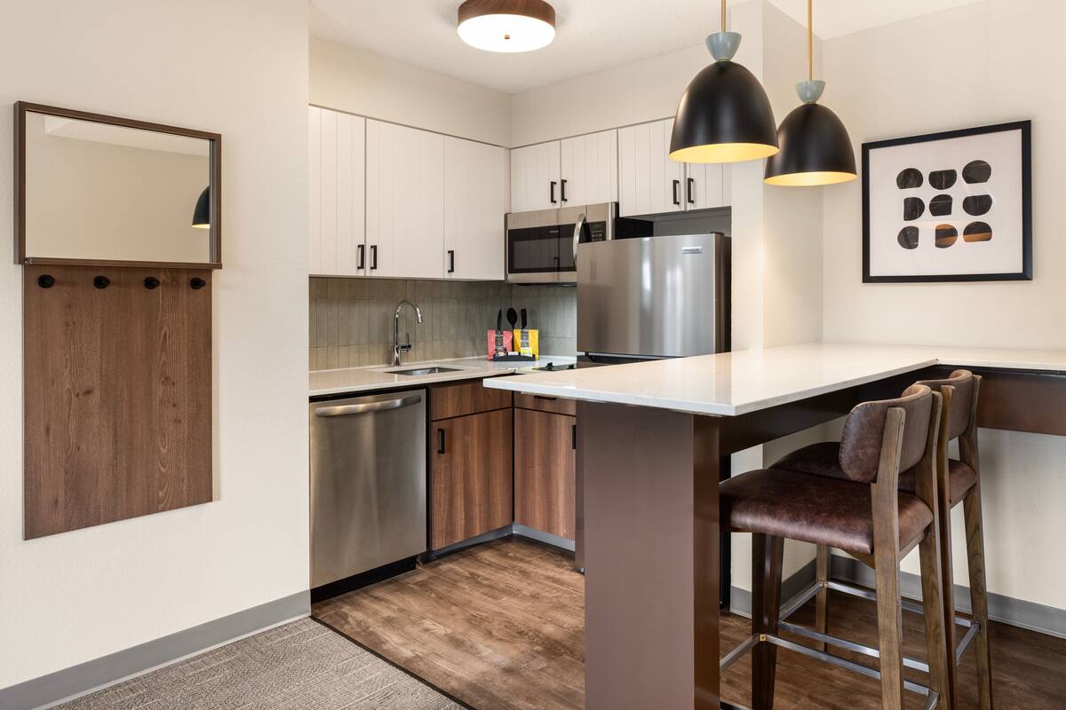 A modern kitchen with white cabinets, stainless steel appliances, and a central island with bar stools.