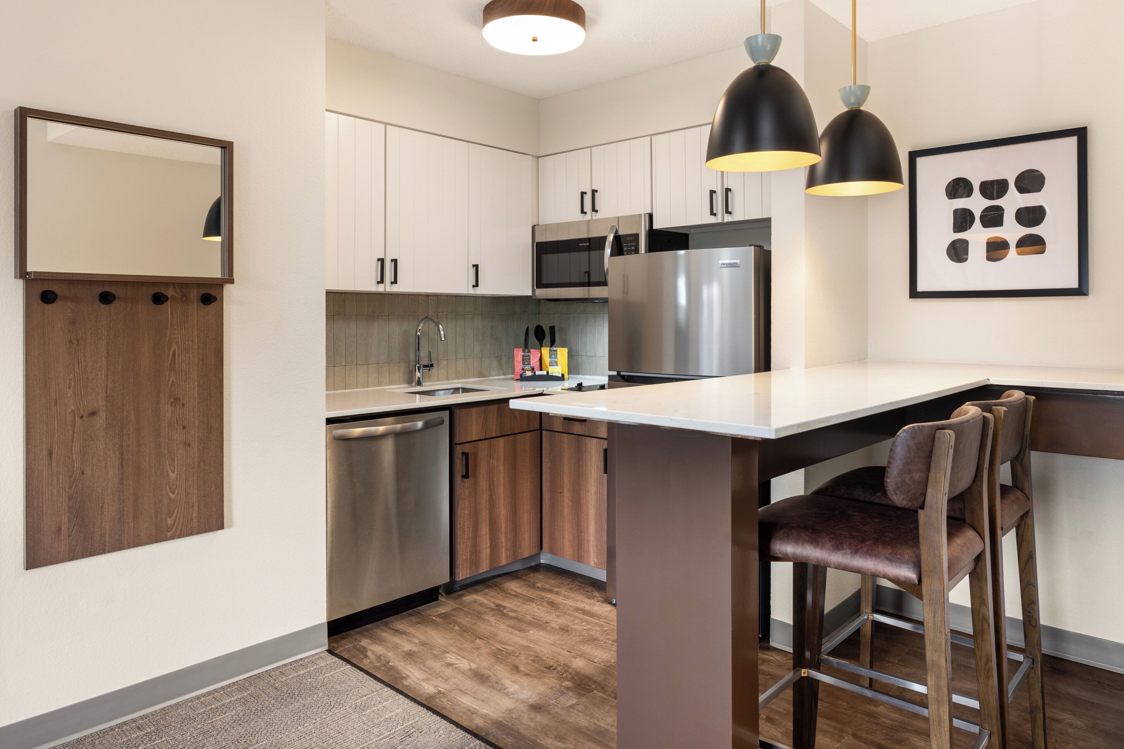 Una cocina moderna con armarios de madera, electrodomésticos de acero inoxidable y un taburete de bar.
