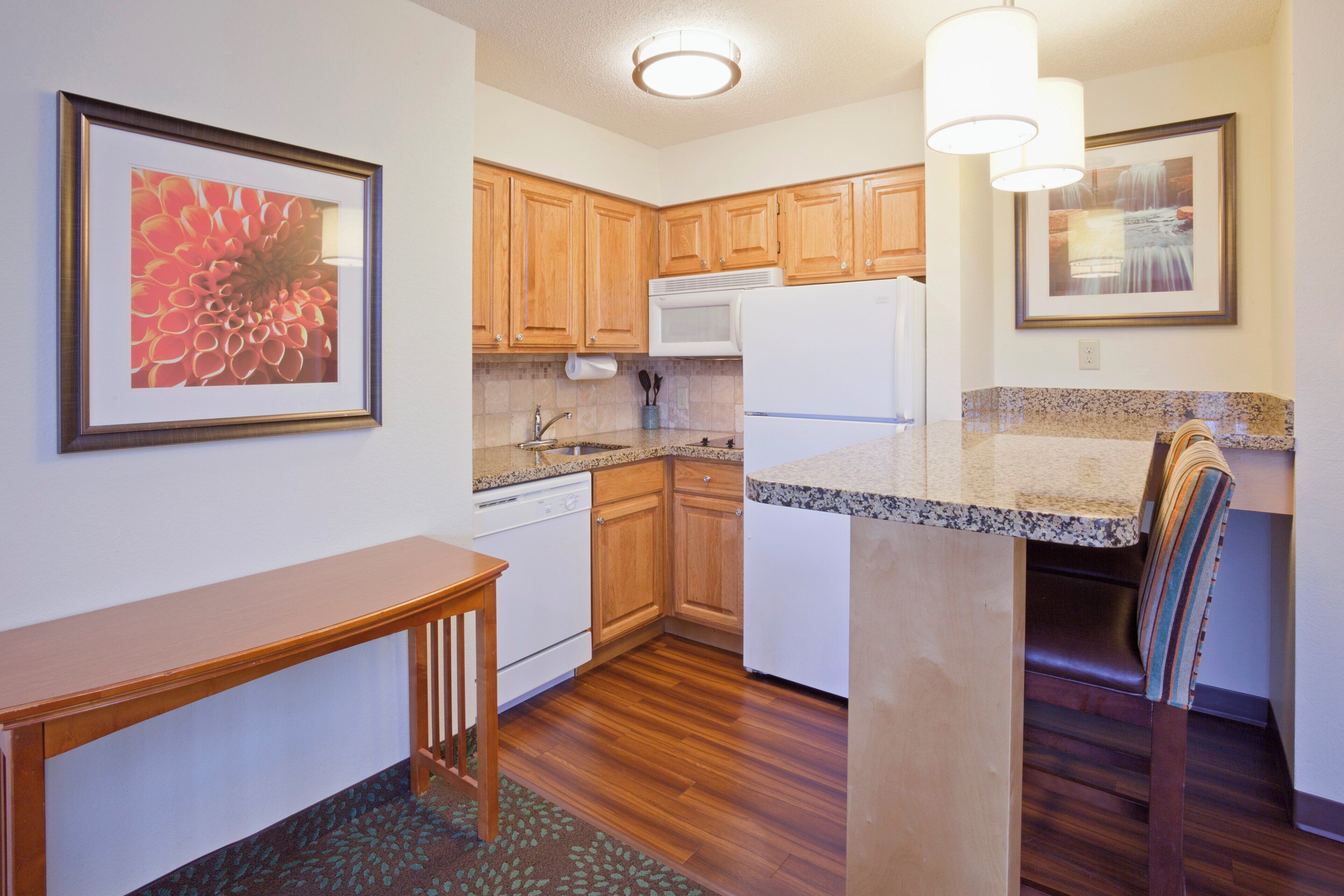A compact kitchen with wooden cabinets, a white refrigerator, and a granite countertop.