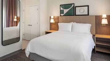 Una habitación de hotel con una cama, una mesita de noche, un espejo y una puerta.