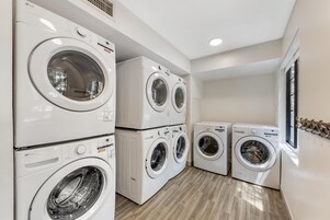 A laundry room with multiple LG washing machines, wooden flooring, and a window providing natural light.