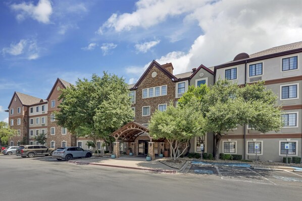 A multi-story hotel with a central entrance, parking area, and a clear sky. - Sonesta ES Suites Austin The Domain Area (Austin)