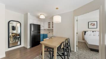 A compact hotel room with a kitchenette, a dining area, and a bed.