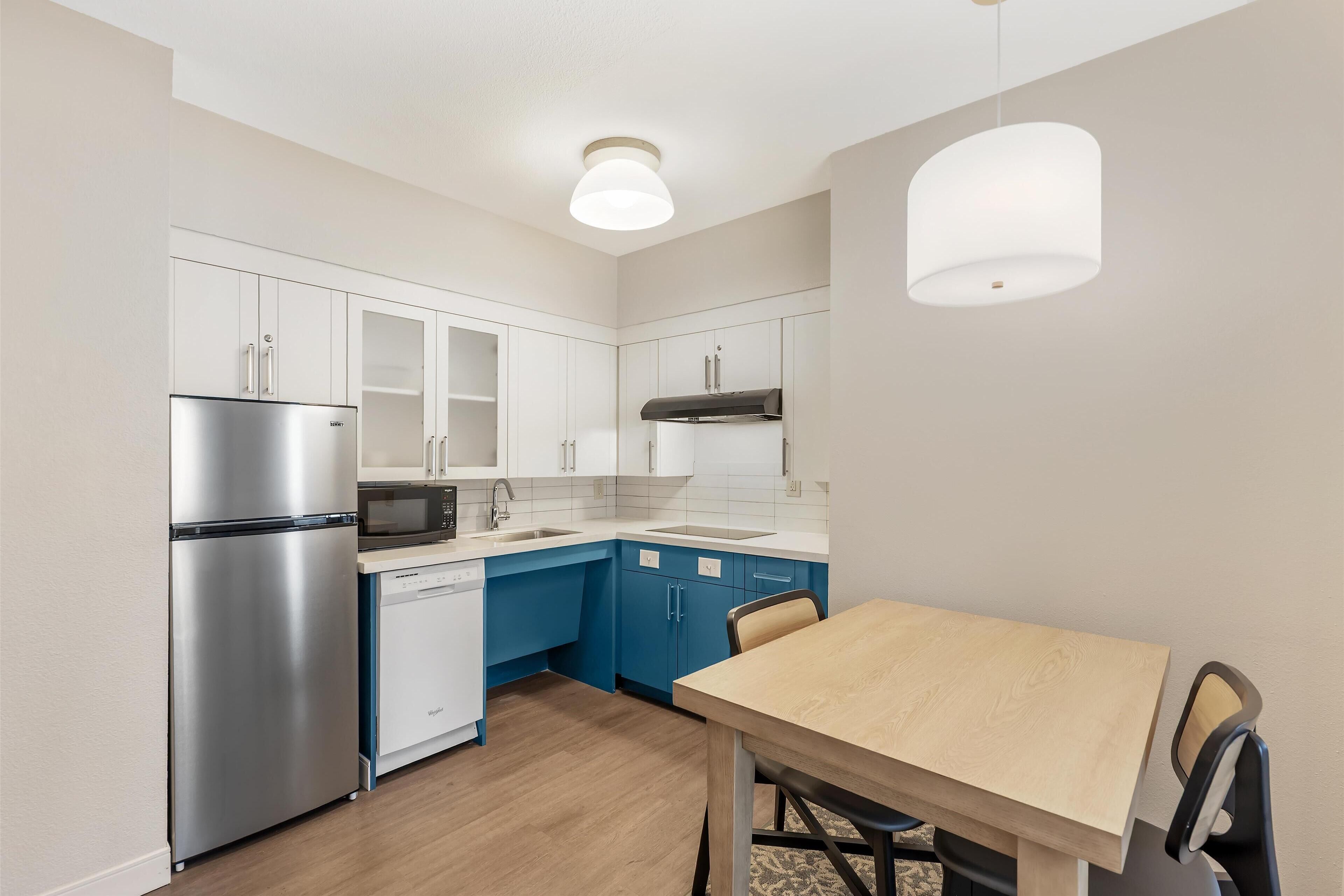 Una cocina moderna con armarios blancos, un refrigerador de acero inoxidable, un microondas y un lavavajillas.