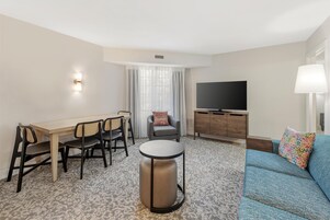 Ett hotellrum med en matplats, en soffa, en TV och en lampa.