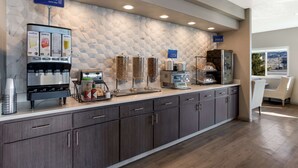 Un bar à jus au design moderne, comprenant un distributeur mural et une machine à café.