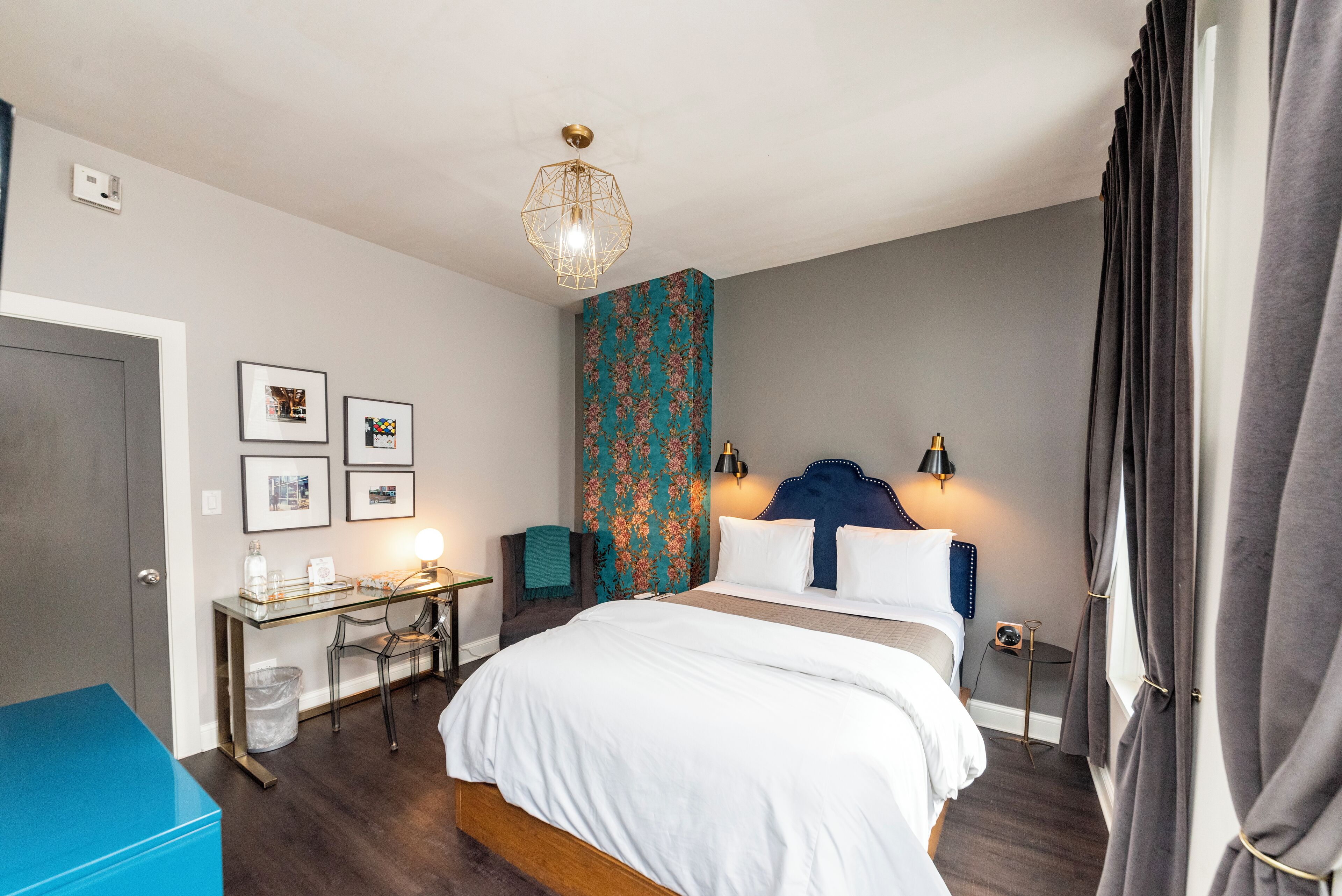 Un dormitorio con cama, escritorio, silla y una pared con estampado floral.