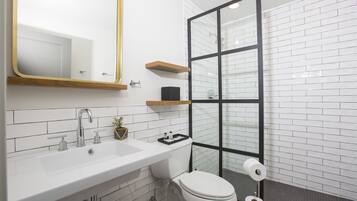Un baño moderno con un lavabo blanco, un inodoro y una cabina de ducha de vidrio.