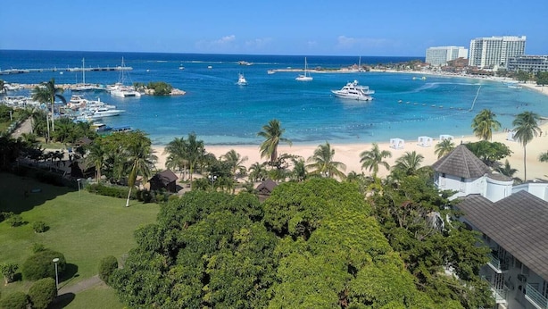 Une vue sur la côte, avec un port de plaisance, une plage et des bâtiments d’hôtel.