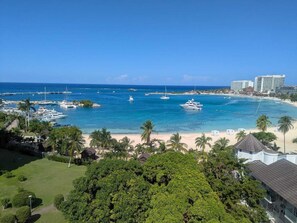 A coastal view with a marina, beach, and hotel buildings. - Beach Side Condos at Turtle Beach Towers (Ocho Rios)