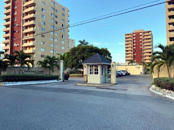 A gated residential area with high-rise apartment buildings, a small utility building, and a sign for Turtle Beach Towers.