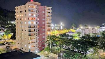 A multi-story hotel with a swimming pool, outdoor seating, and a view of the surrounding area.