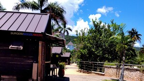 Un bâtiment avec une enseigne indiquant « BURGERS / BOISSONS / BIÈRES » et une entrée dallée.
