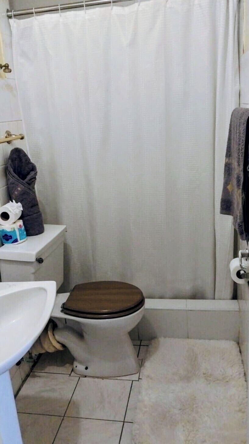 Un baño con inodoro, lavamanos y cortina de ducha.