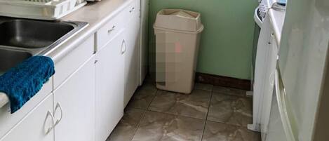 A compact kitchen with white cabinets, a microwave, a sink, and a window.