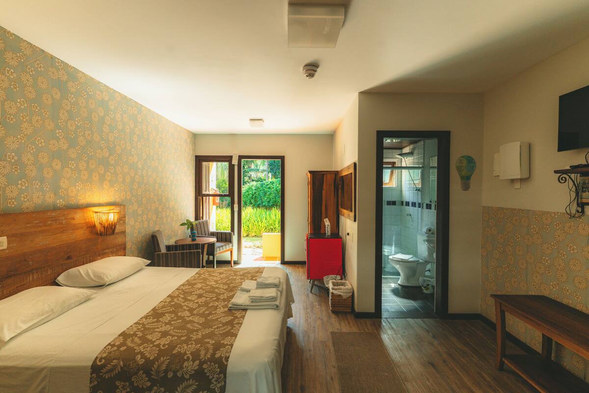 A hotel room with a bed, a desk, and a bathroom visible through an open door.