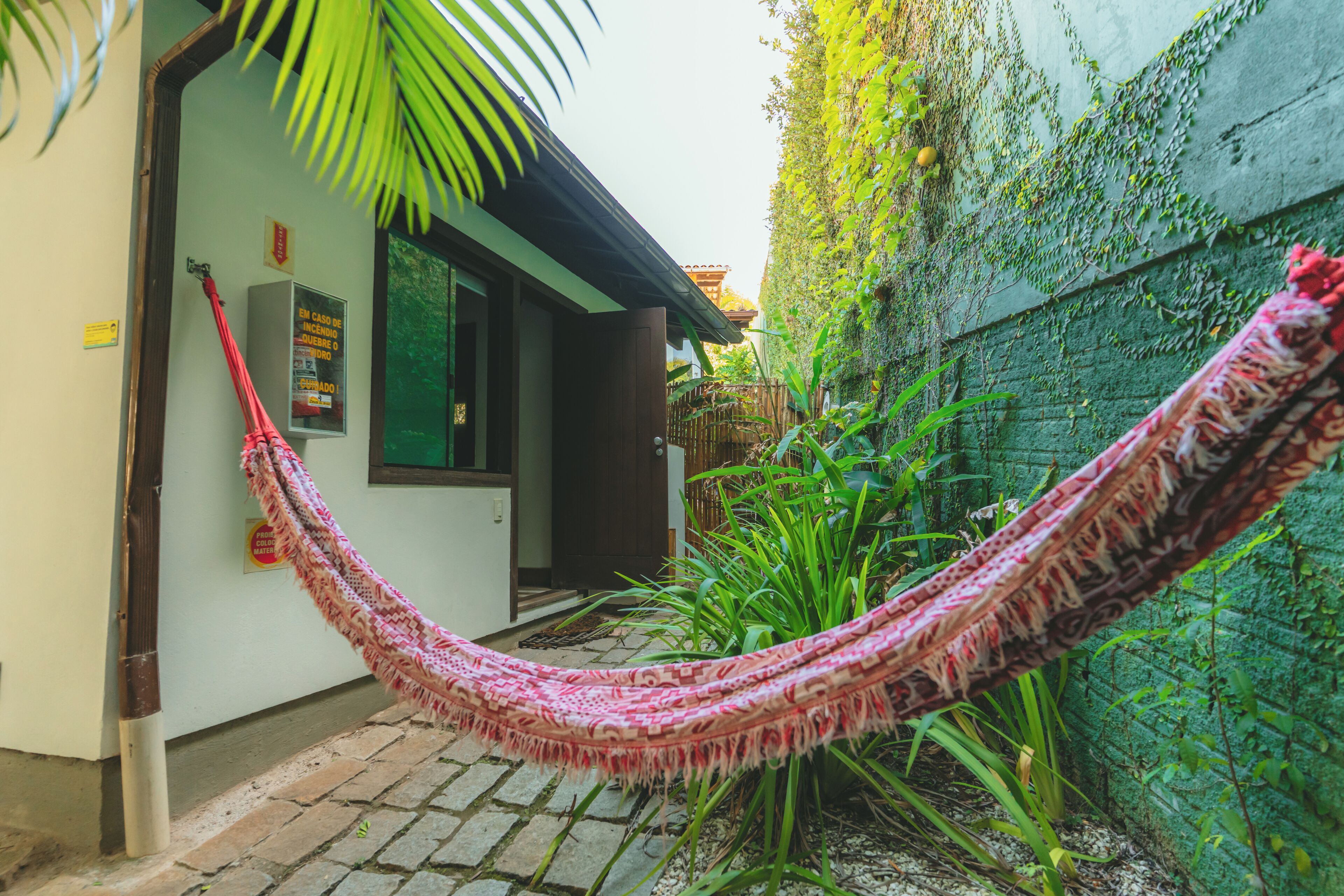 A hammock tied between a building and a wall, with a door and a window visible.