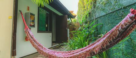 A hammock tied between a building and a wall, with a door and a window visible.