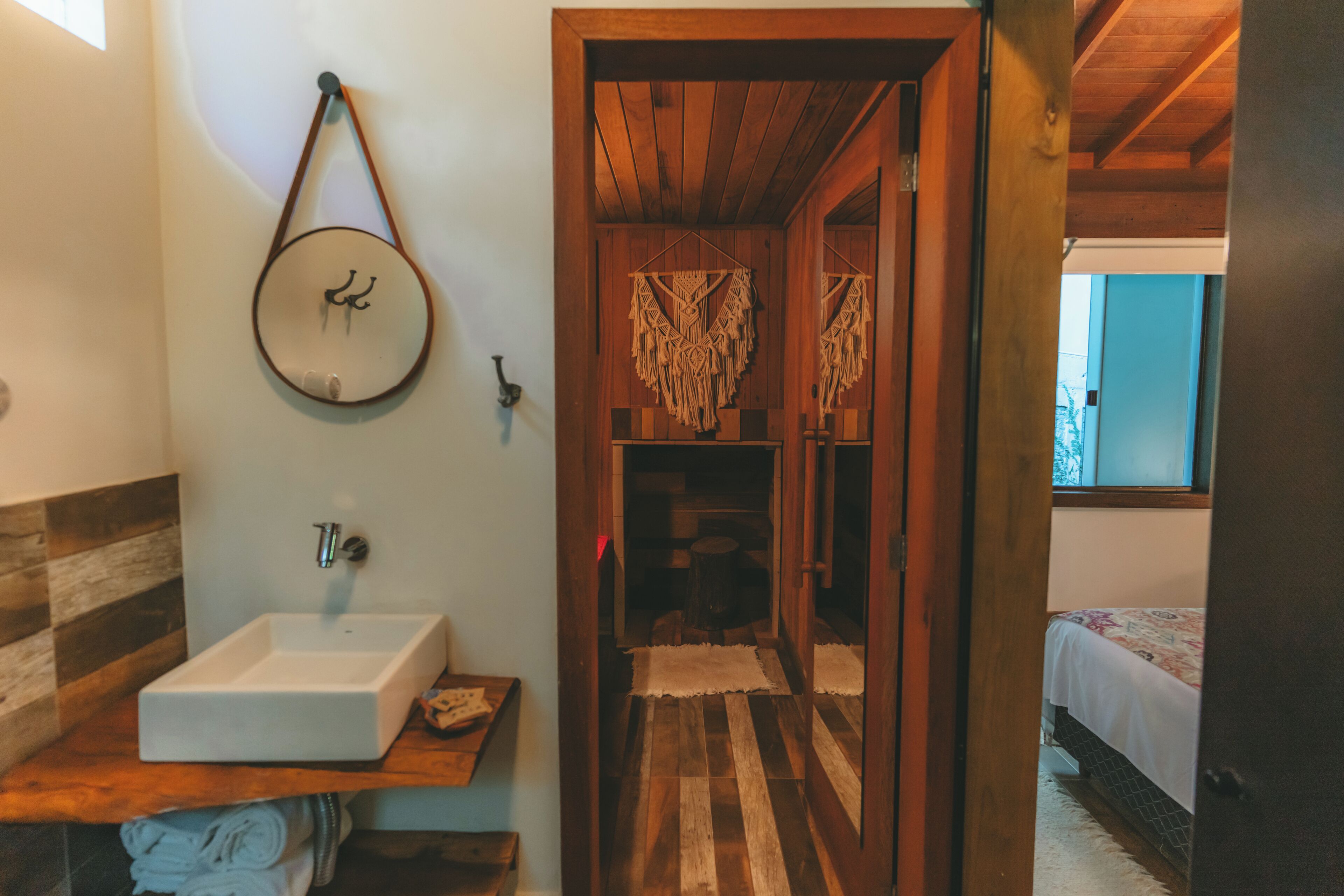 Ein Badezimmer mit einem weißen Waschbecken, einem Holzkosmetikschrank und einem Spiegel mit einem hängenden Schmuckstück.