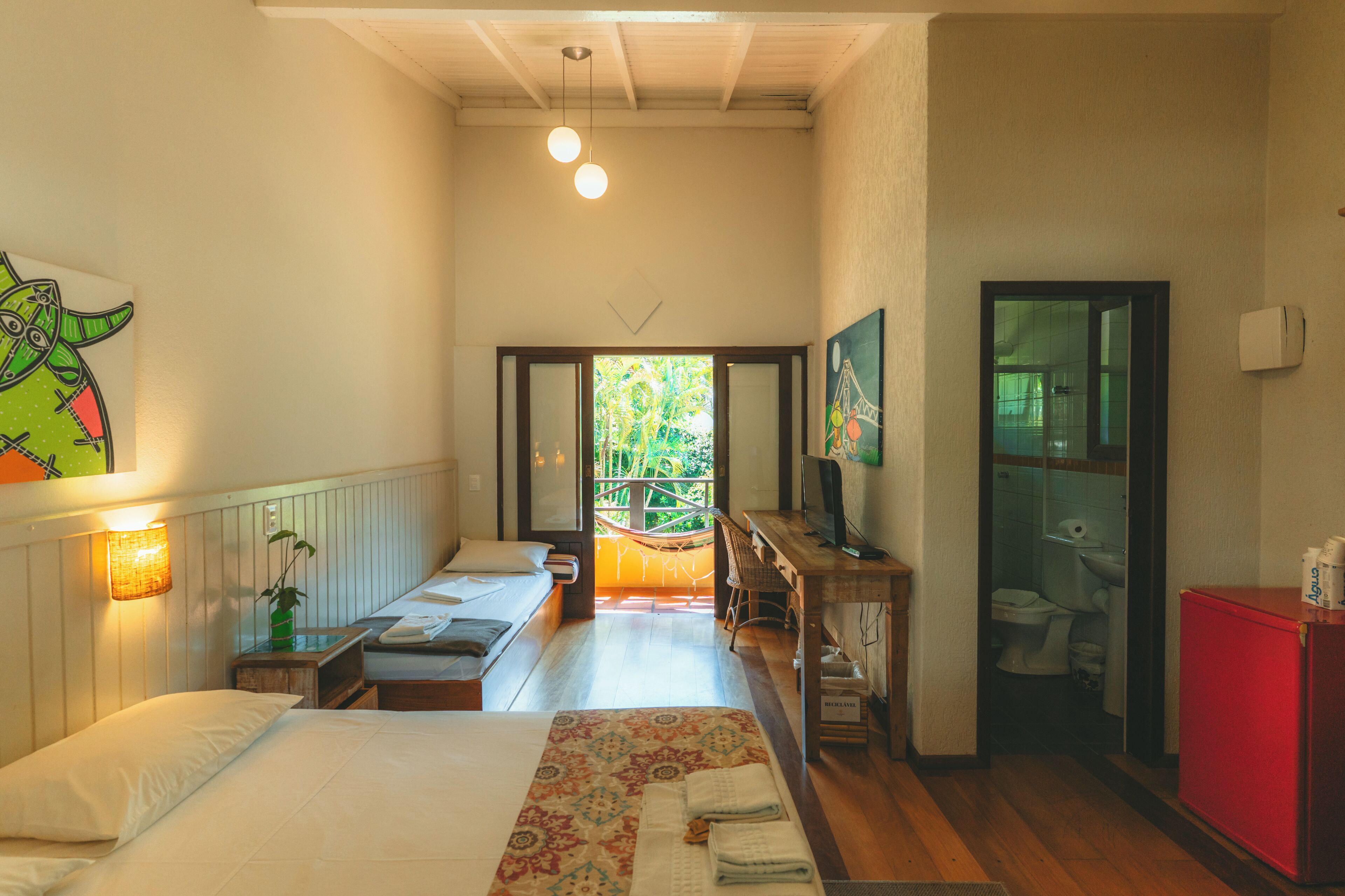 Habitación de hotel con cama, escritorio y vista a un jardín a través de un ventanal.