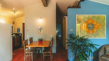 Un comedor con una mesa y sillas de madera, una planta en maceta y una pared con un cuadro grande enmarcado.