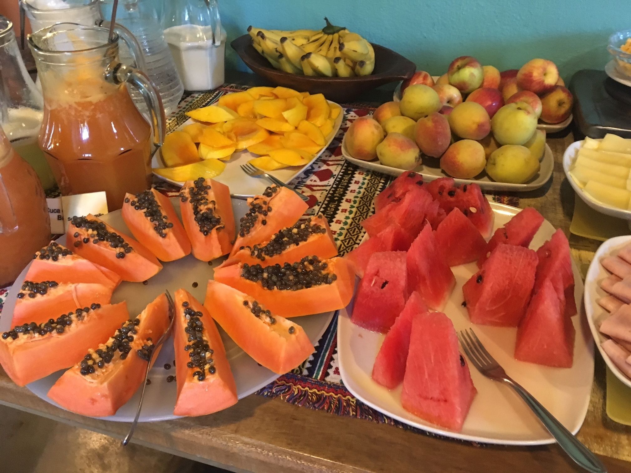 A breakfast buffet with various fruits and a pitcher of juice.