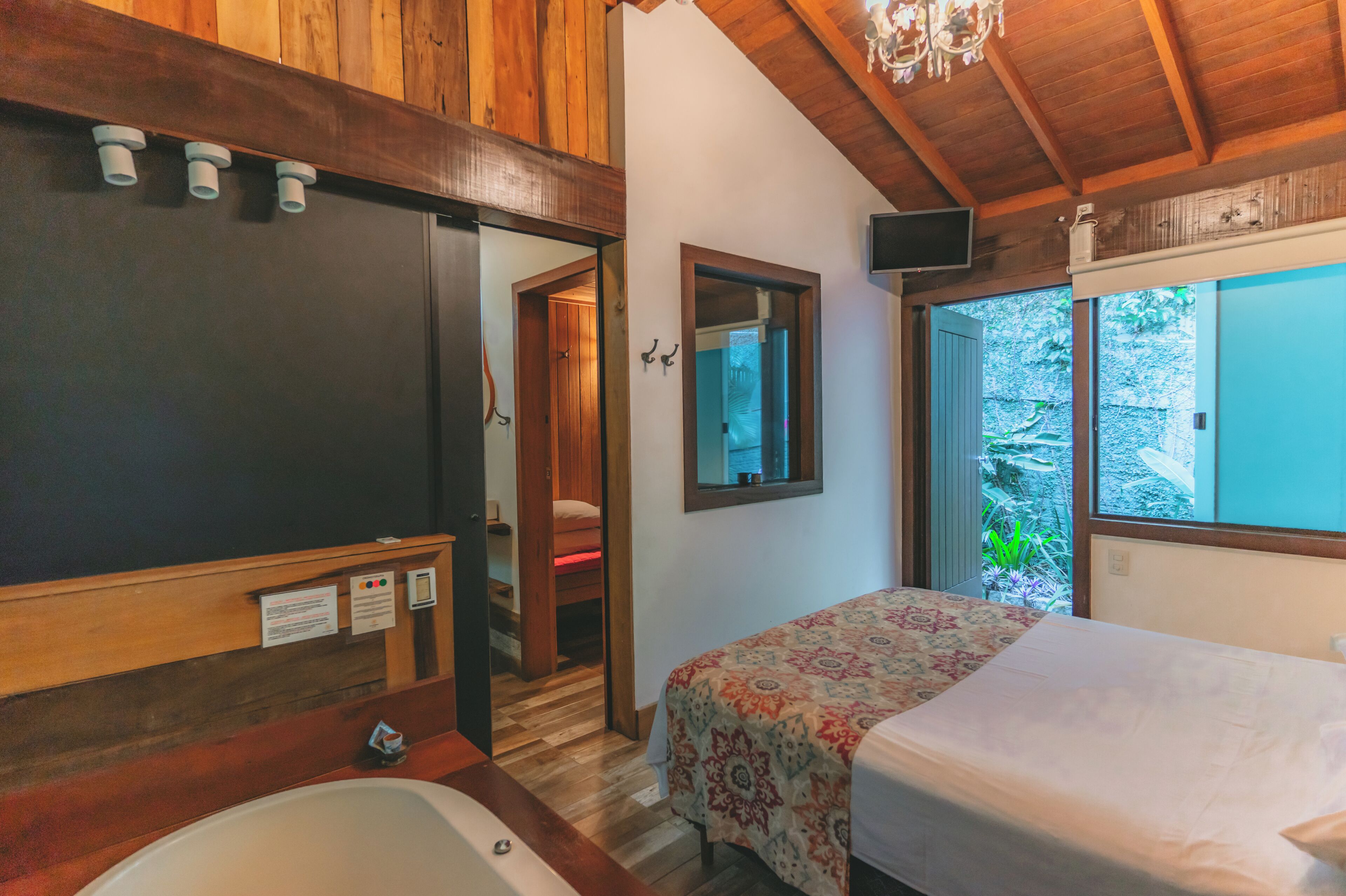 Une chambre à coucher avec un lit, un plafond en bois, une fenêtre et une salle de bain avec une baignoire.