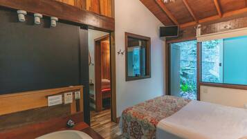 Une chambre à coucher avec un lit, un plafond en bois, une fenêtre et une salle de bain avec une baignoire.