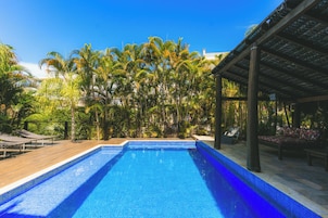 Una piscina al aire libre, sillones reclinables de piscina