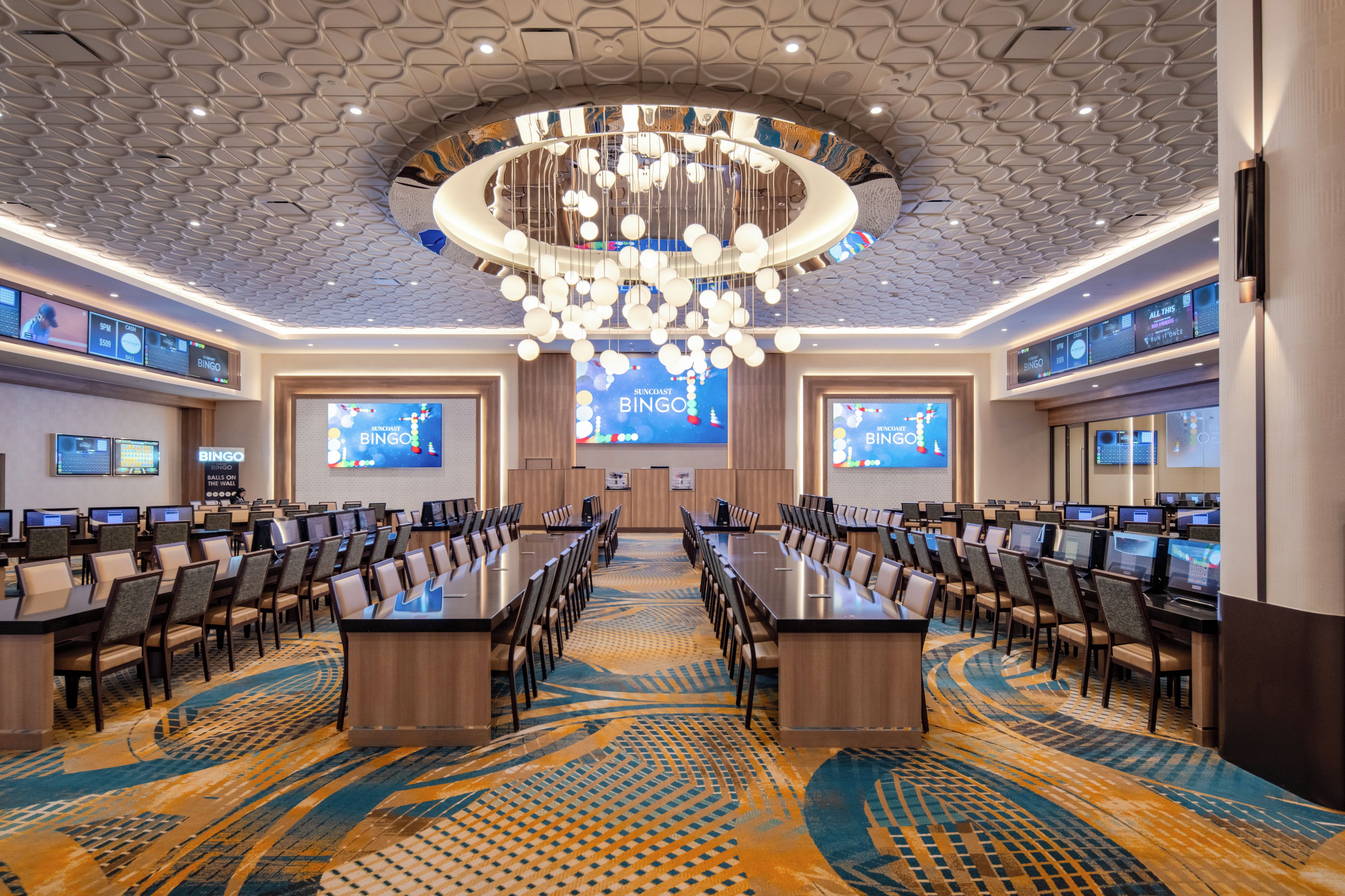 A conference room with a long table, multiple chairs, and a large screen displaying a game.
