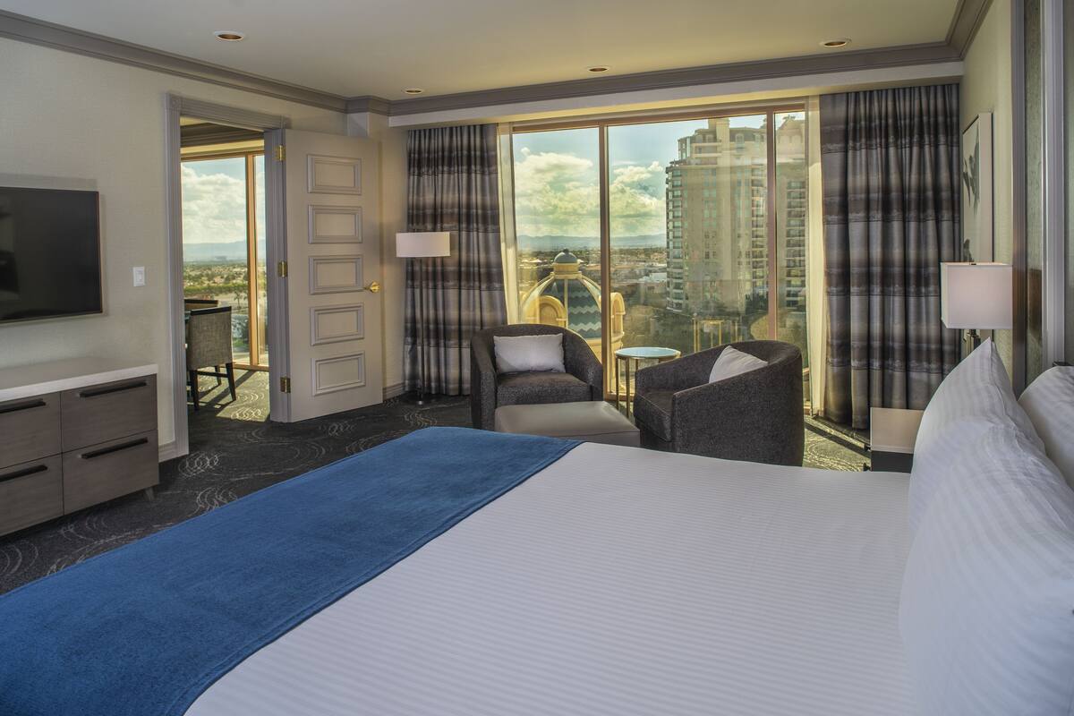 Habitación de hotel con una cama grande, televisión, escritorio y vistas a la ciudad.
