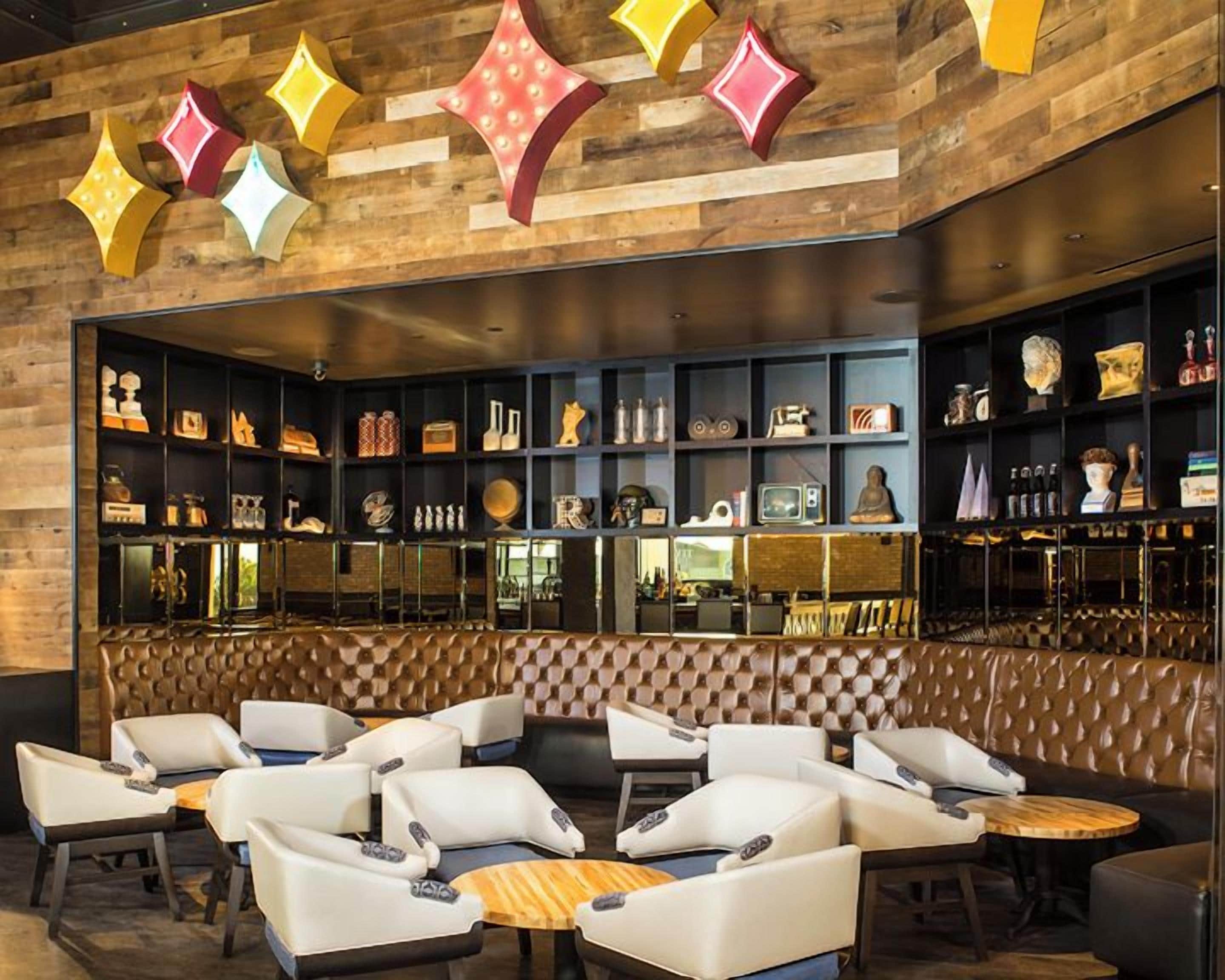 Zona de bar con asientos y estantes llenos de objetos varios.