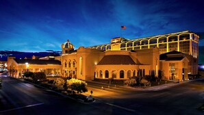 Un edificio grande e histórico con una cúpula destacada y ventanas arqueadas, que presenta una fachada bien iluminada y una bandera en la parte superior.