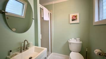 A bathroom with a sink, toilet, and a window.