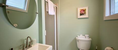 A bathroom with a sink, toilet, and a window.