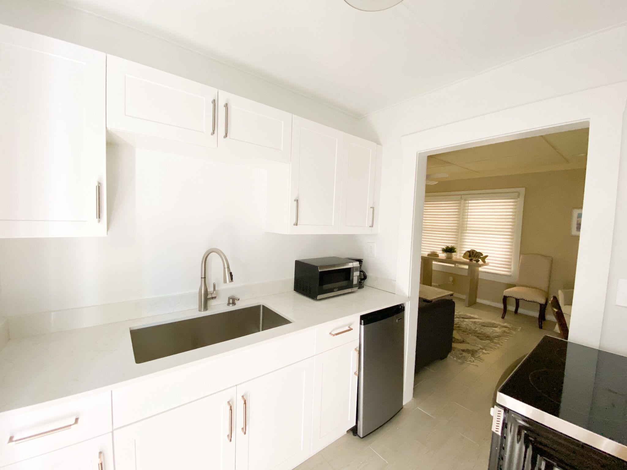 A modern kitchen with white cabinets, a stainless steel sink, and a black countertop.