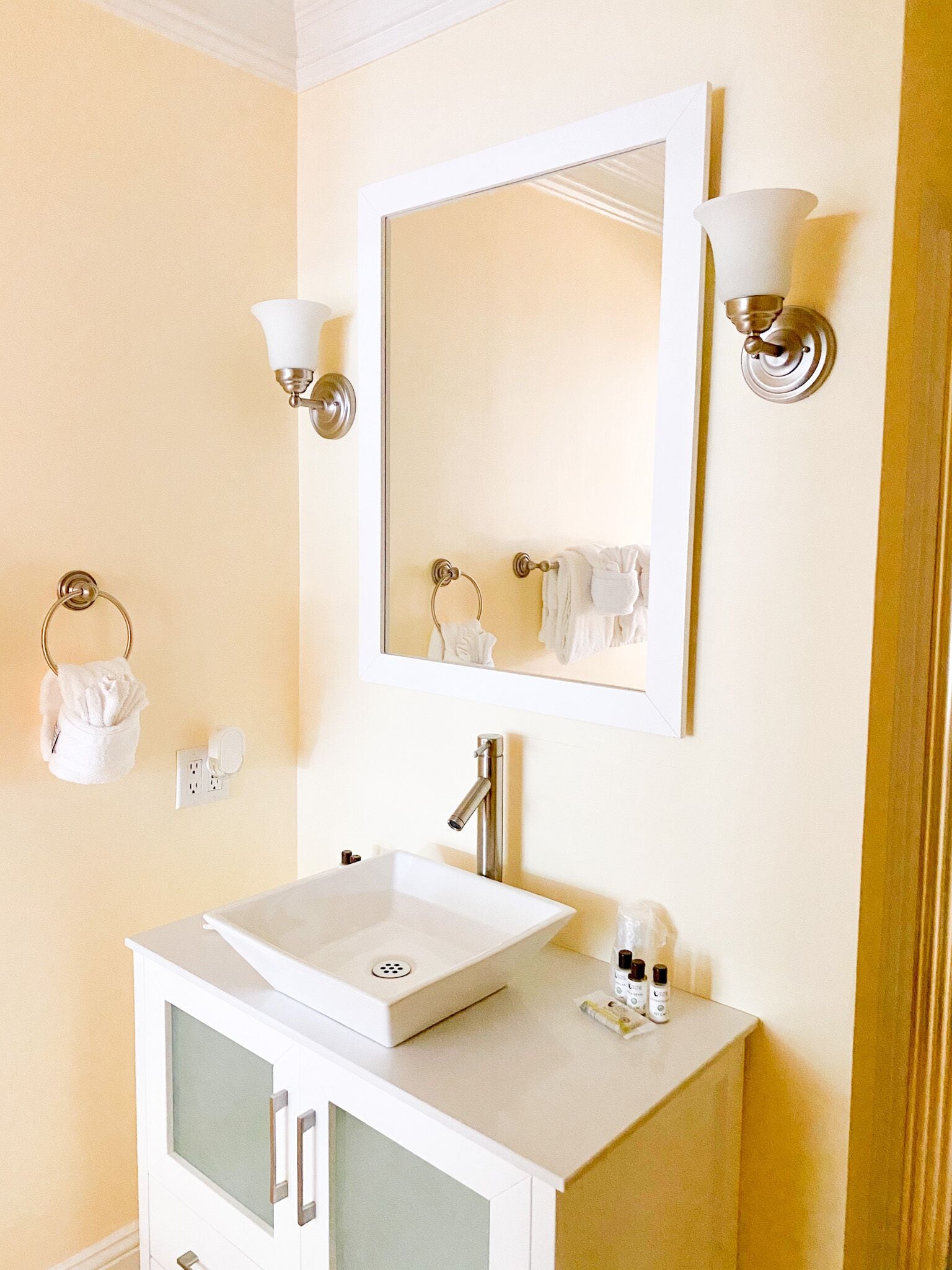 Une salle de bain avec un lavabo blanc, un miroir et deux appliques murales.