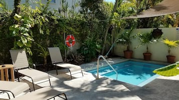 Een buitenzwembad, ligstoelen bij het zwembad