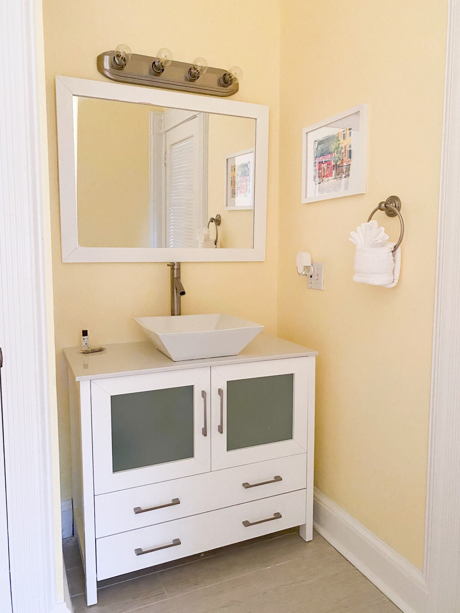 A bathroom with a white vanity, a large mirror, and a sink.